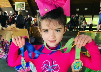 A youthful Irish dancer holding up her medals