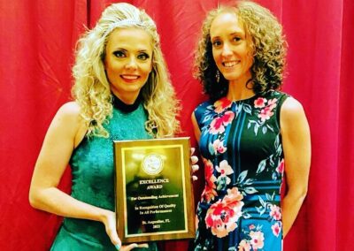 Two Irish dancing teachers holding up their accolade
