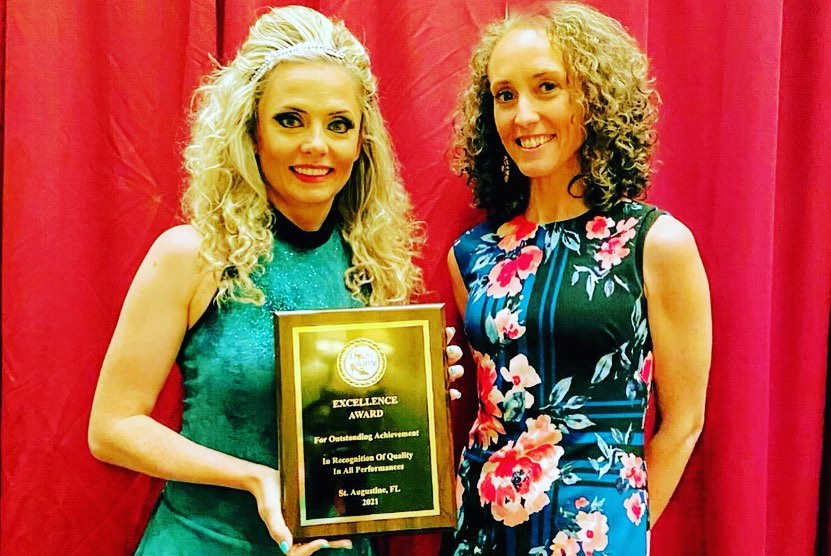 Two Irish dance teachers holding up award 