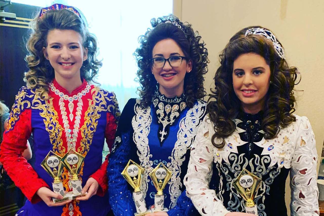 Three Irish Dancers holding trophies 